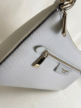 Load image into Gallery viewer, A close-up of a light gray pebbled leather handbag with gold-tone hardware, featuring a front zip pocket and a small leather brand tag that reads 'kate spade new york'.
