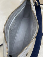Load image into Gallery viewer, Close-up of the interior of a handbag, showing a light gray patterned lining, a gold-tone zipper, and a dark blue textured strap on the right side.
